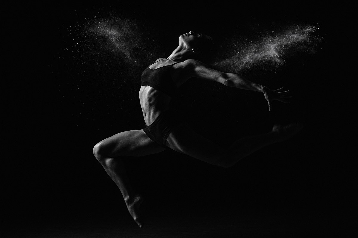 A dancer mid-leap in a burst of powder